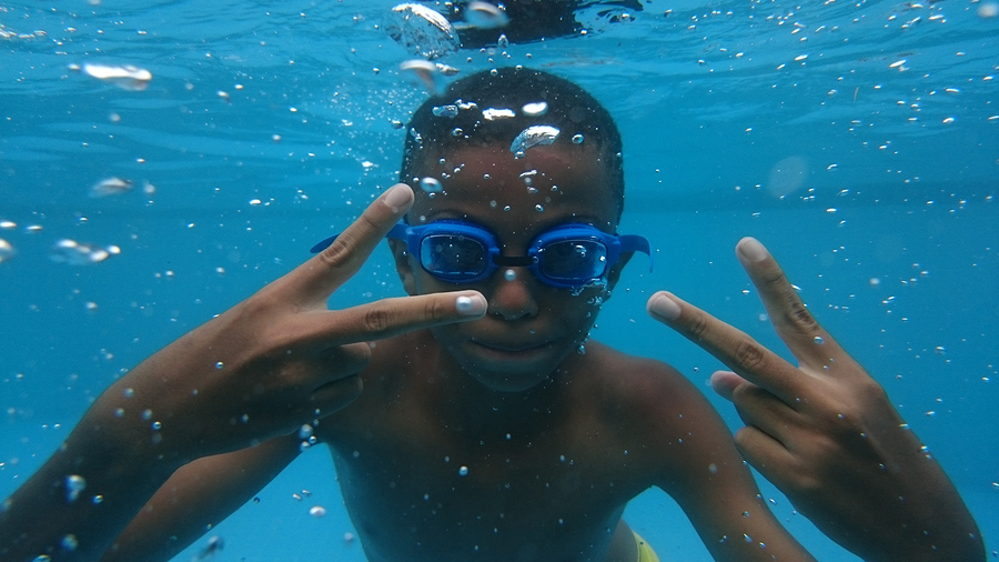 Black child diving in the blue pool